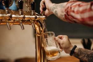 A man pours a glass of beer from a tap in a pub.