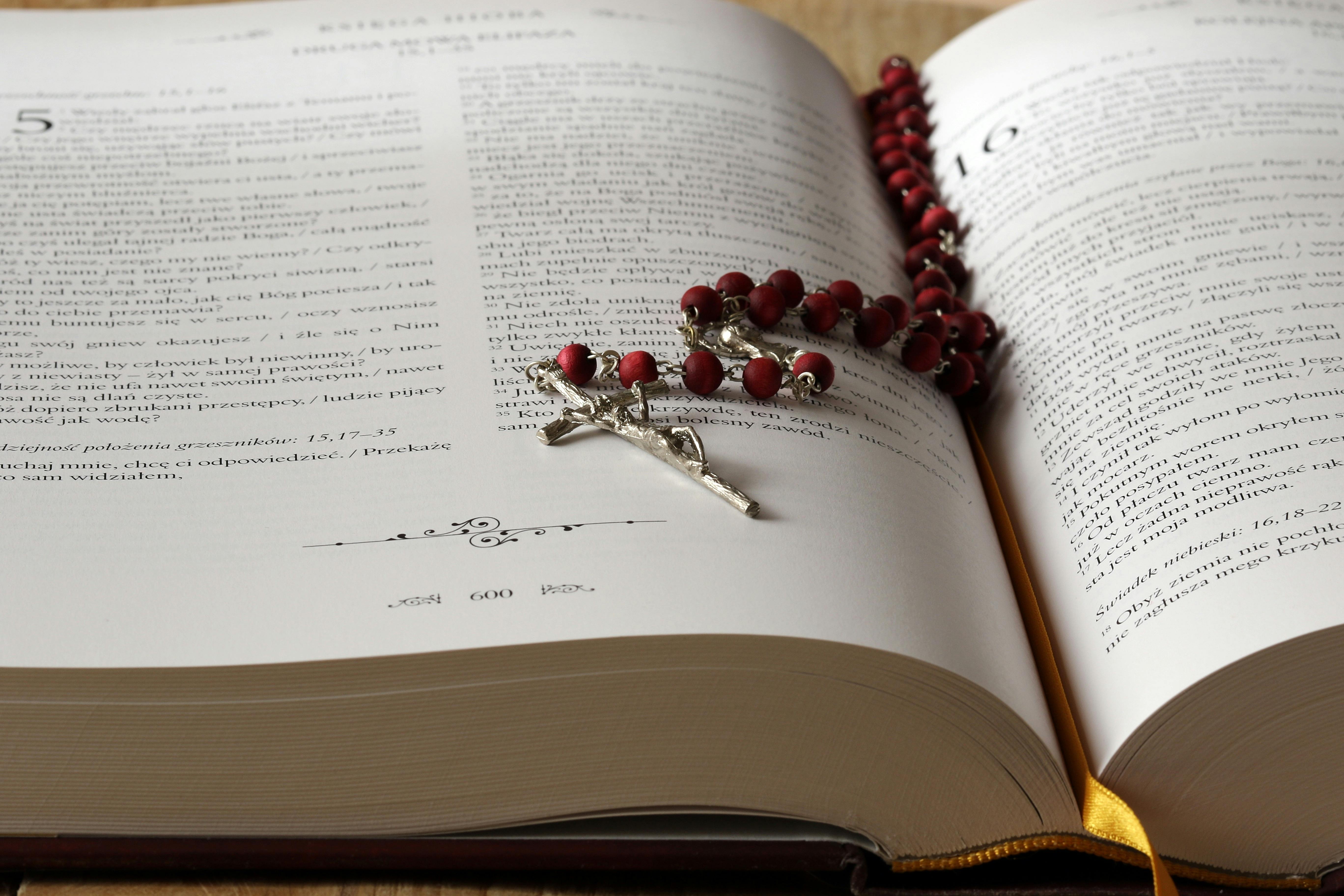 Rosary beads sit on an open copy of a bible.