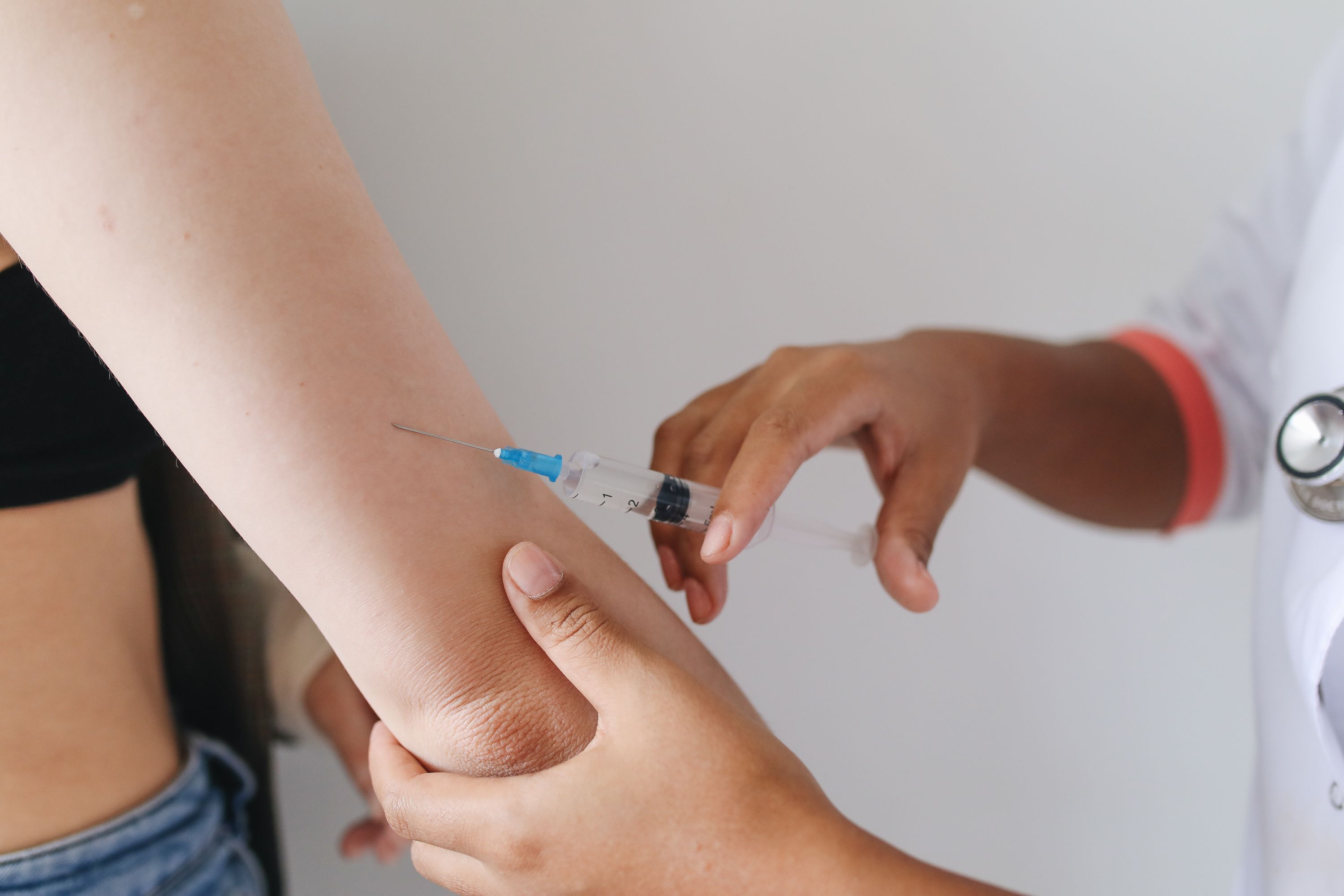 A medical proffessional give a person a shot with a syringe.
