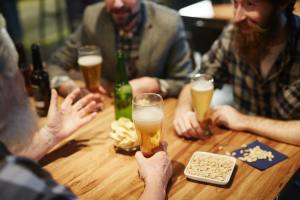 PEOPLE SIT AROUND A TABLE DRINKING BEER
