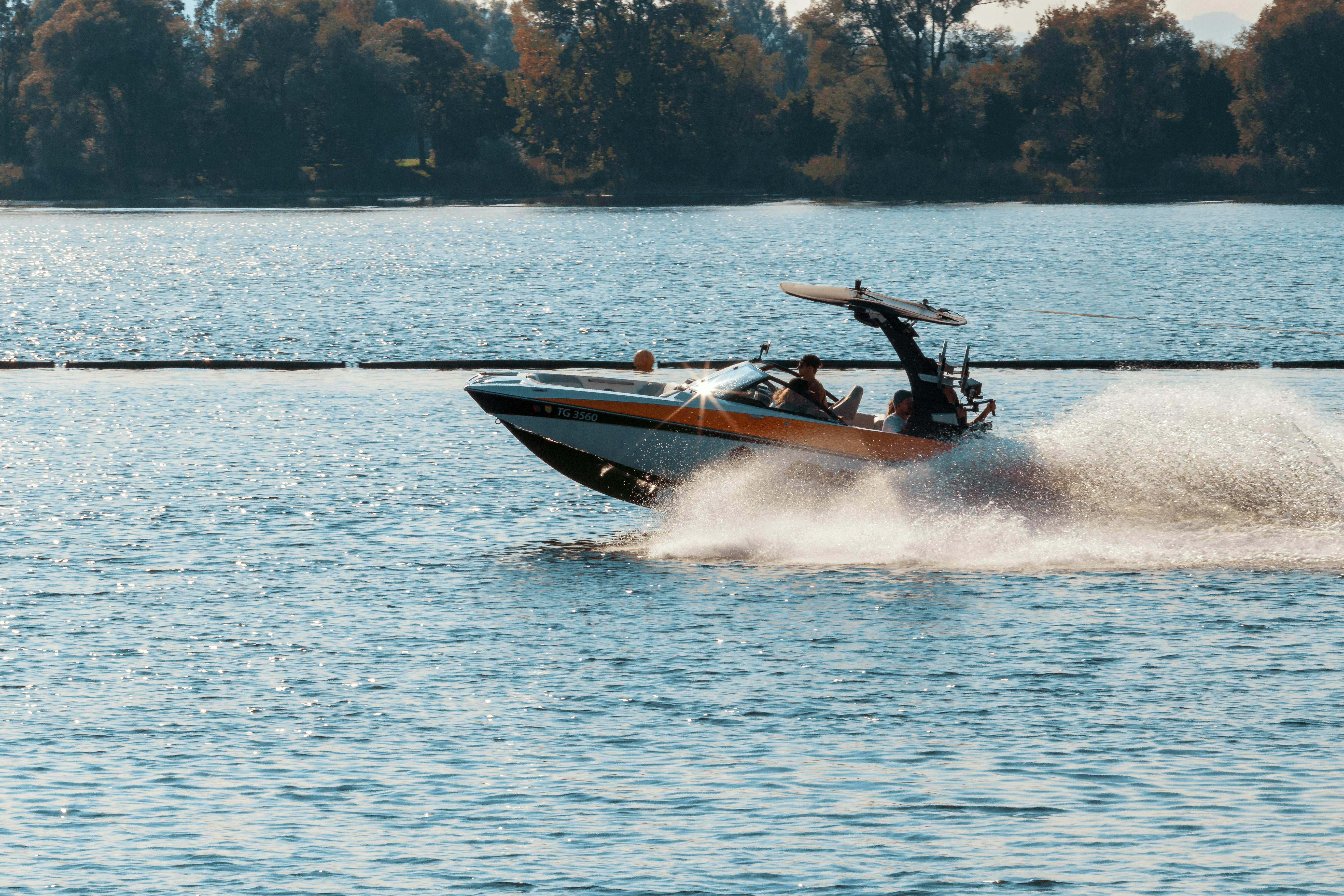 A speed boat travels along a lake.
