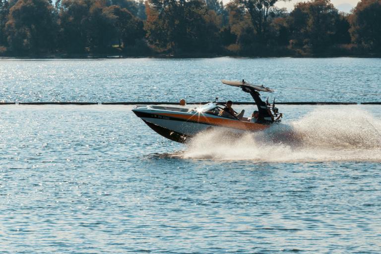 A speed boat travels along a lake.