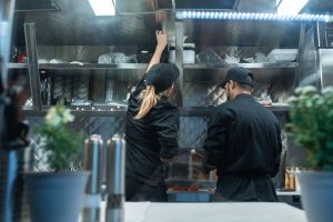 Two people work in a restaurant kitchen.
