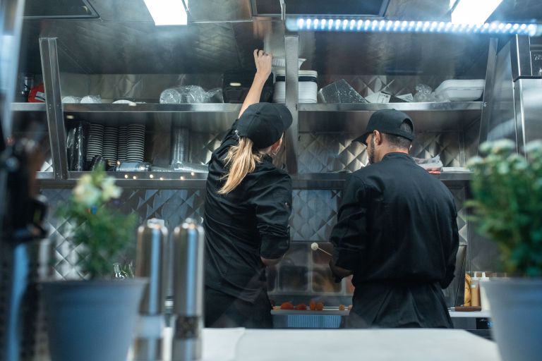 Two people work in a restaurant kitchen.