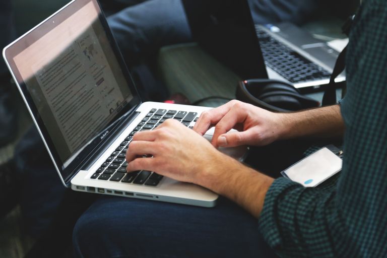 A man types on a laptop computer.