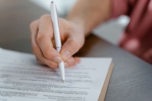 a person signs a contract with a pen