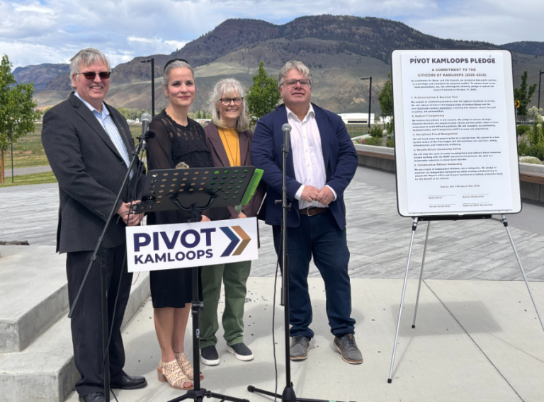 Four people standing at an outdoor news conference.