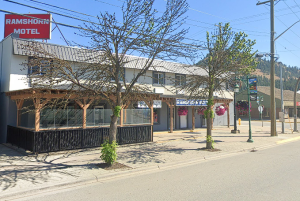 A motel on a street bordered by a few trees.
