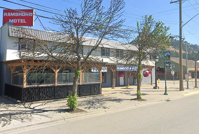 A motel on a street bordered by a few trees.