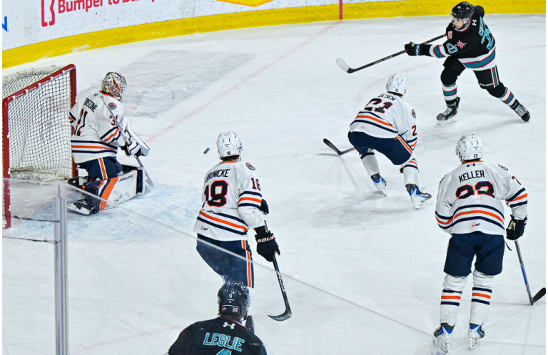Hockey player shoots toward an opposing goalie.