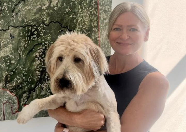 A blonde woman awkwardly holds a dog.