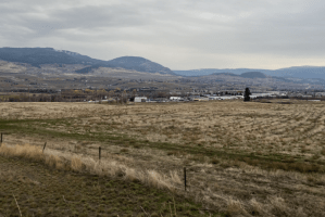An open field with some buildings and mountains in the background.