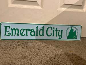 A metal sign reading Emerald City leans against a door.