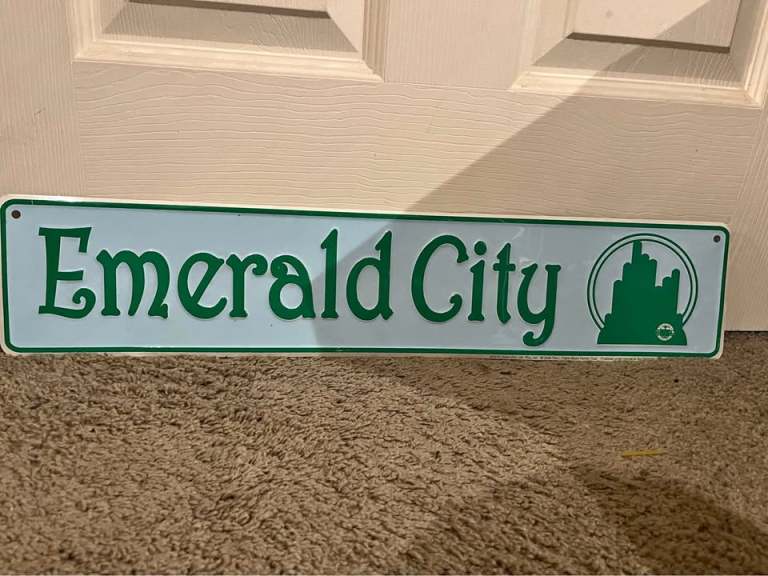 A metal sign reading Emerald City leans against a door.