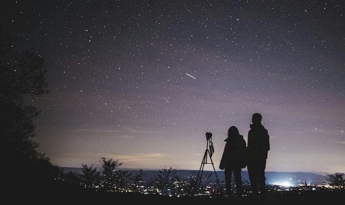 Two people using telescopes looking at a starry sky.