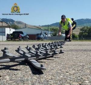 An RCMP officer deploys a spike belt.
